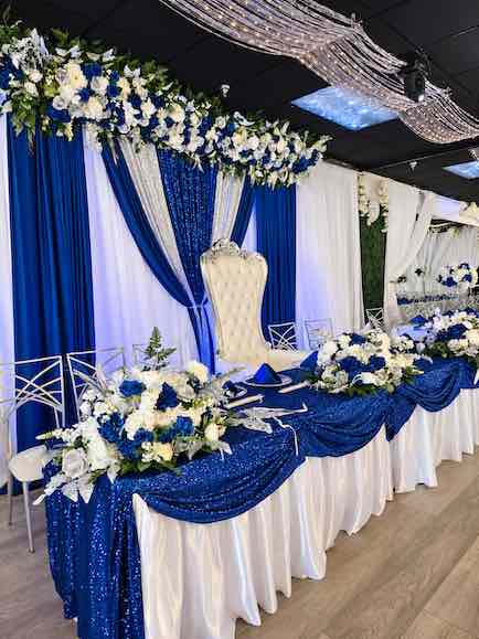 Royal blue and white main table with flowers and a throne