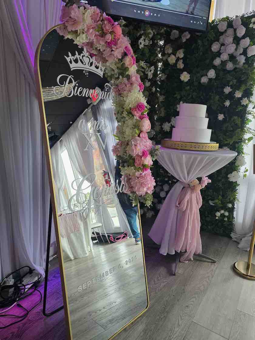 Personalized welcome mirror beside a cake and pink floral décor