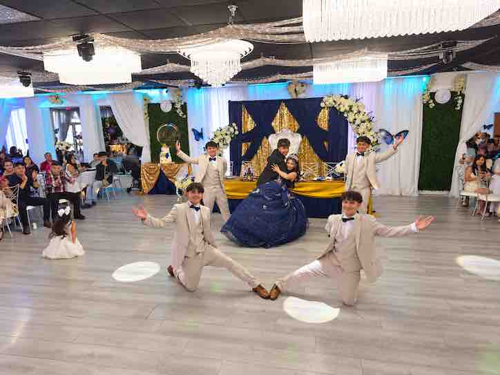 Quinceañera in a royal blue dress dancing with her court