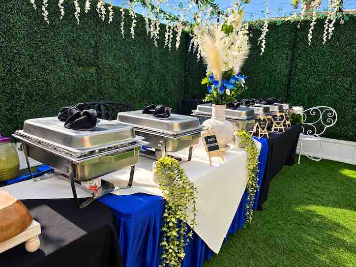 Blue and white buffet setup in the green garden beneath a floral ceiling